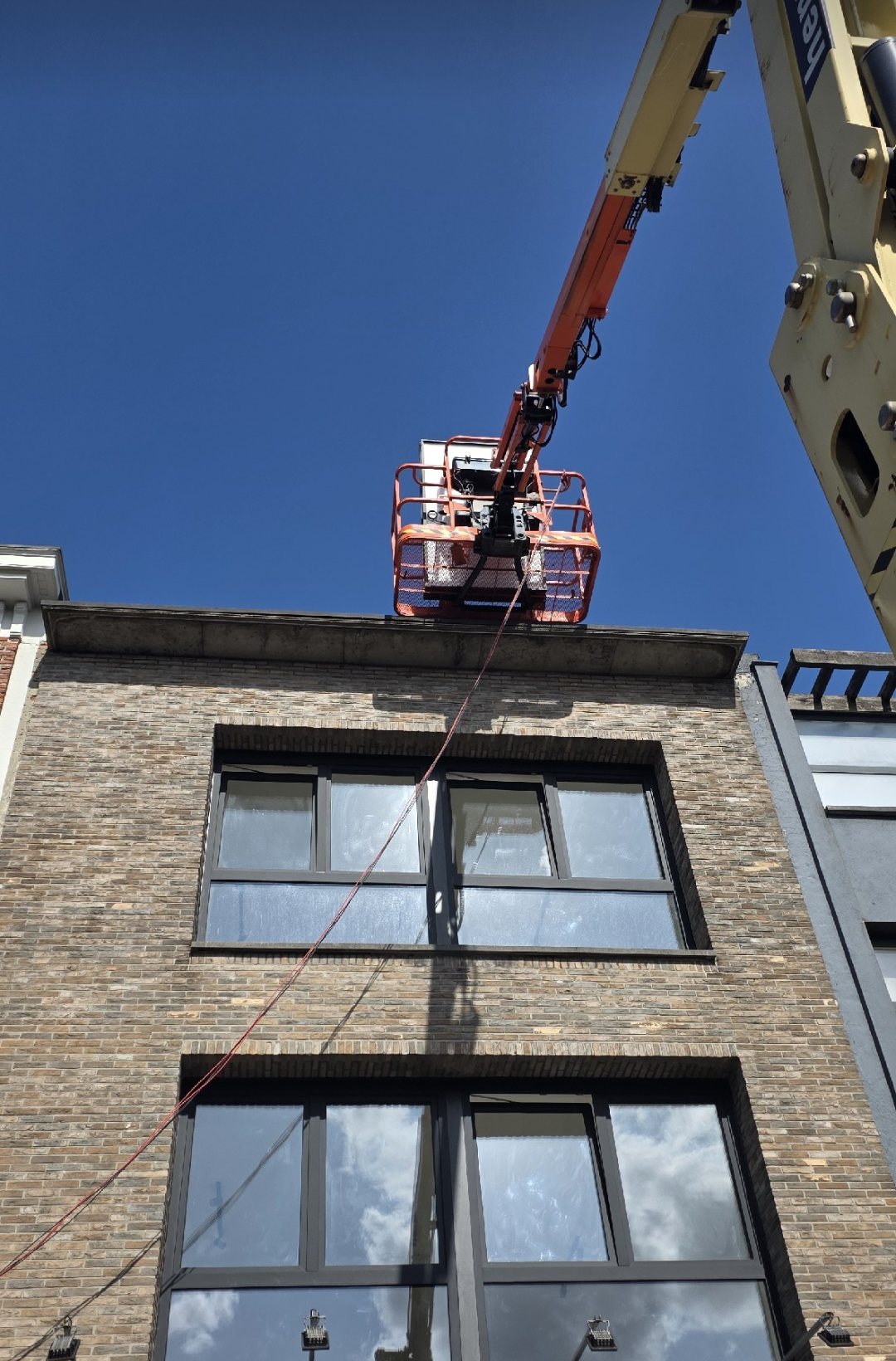 An OX crew member working from a boom lift on a building facade